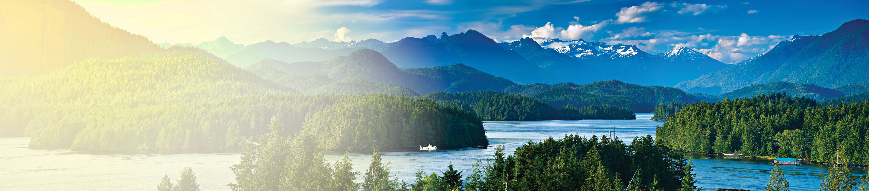 A large lake surrounded by pine forests and snowy mountains.